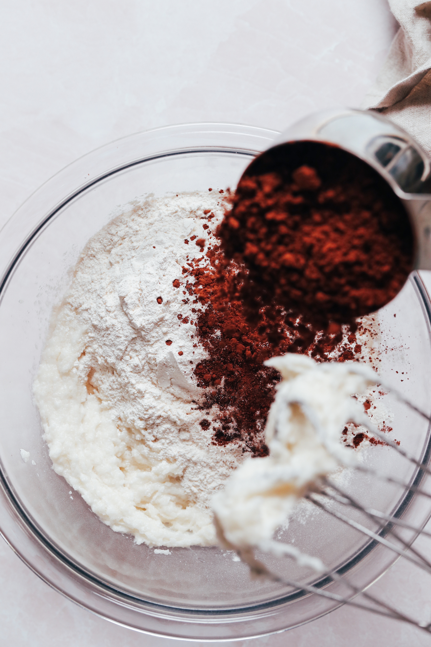 Pouring cocoa powder from a measuring cup into a bowl