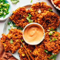 Platter of vegan gluten-free kimchi rice fritters with sriracha sour cream sauce