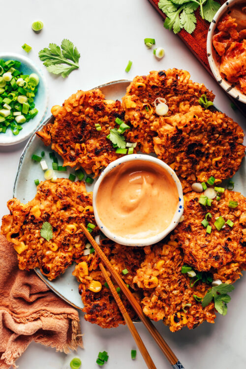 Platter of vegan gluten-free kimchi rice fritters with sriracha sour cream sauce