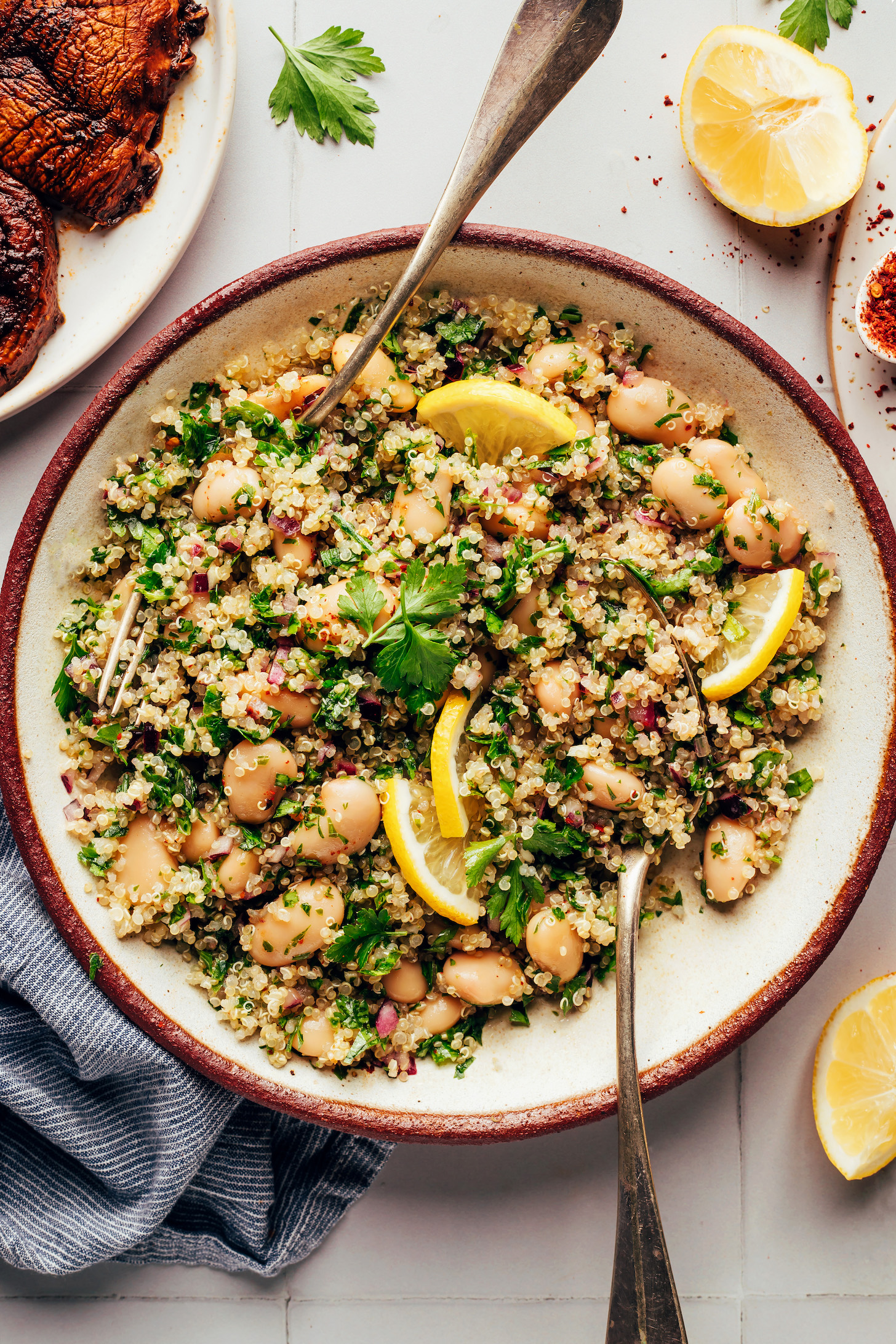 Spoon and fork in a bowl of white bean quinoa salad topped with lemon slices