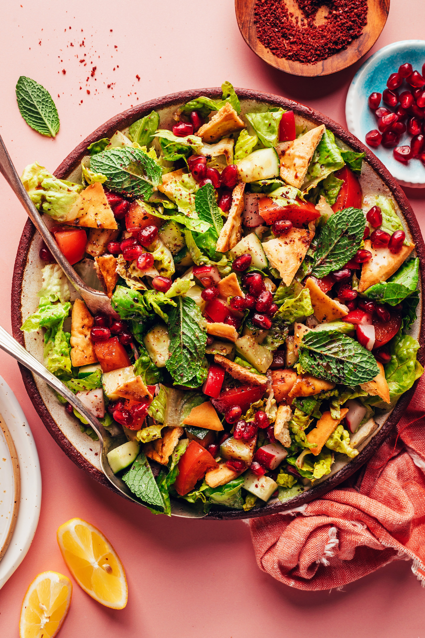 Serving utensils resting on a plate of our easy fattoush salad recipe