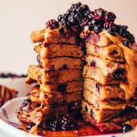 Photo of a tall stack of plantain pancakes with toppings and a slice removed