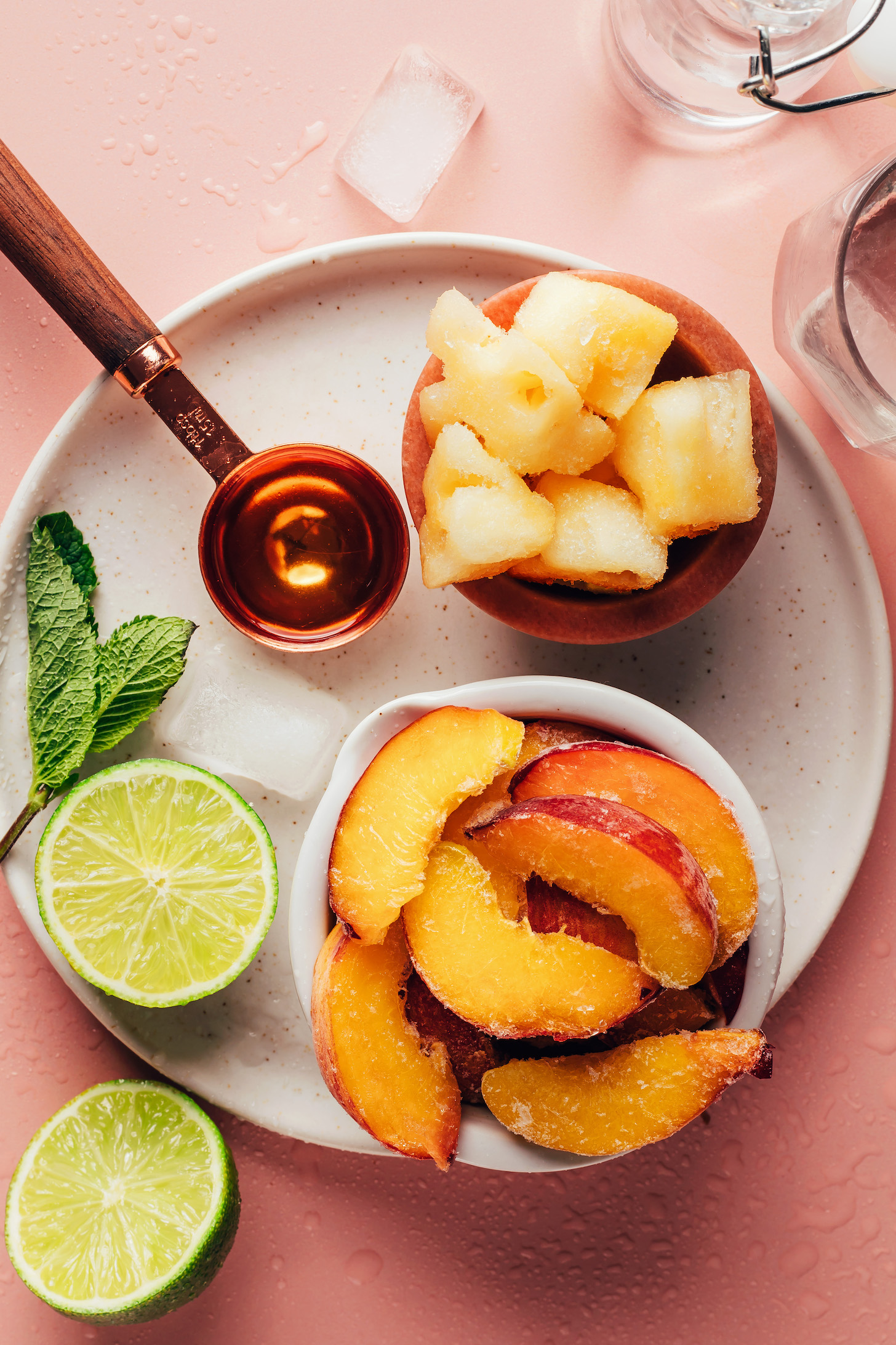 Frozen peach slices, frozen pineapple chunks, maple syrup, water, ice cubes, fresh mint, and limes