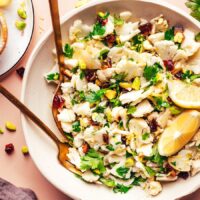 Fork and spoon resting in a bowl of our easy raw chopped cauliflower salad recipe