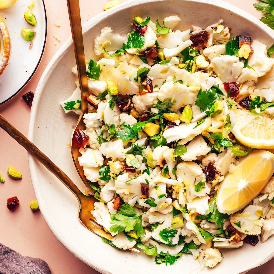 Fork and spoon resting in a bowl of our easy raw chopped cauliflower salad recipe
