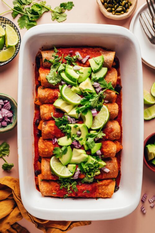 Ceramic casserole dish filled with vegan butternut squash black bean enchiladas