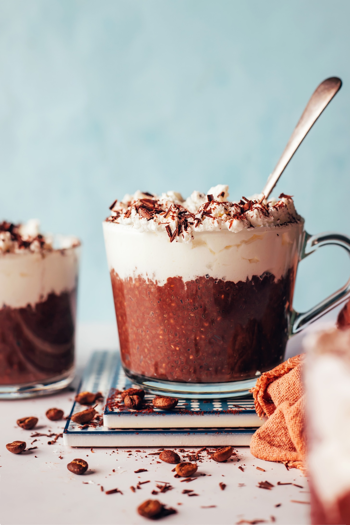 Mug of mocha chia pudding topped with coconut whipped cream and shaved chocolate