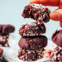 Holding a partially eaten chocolate tahini cookie over a stack of more cookies