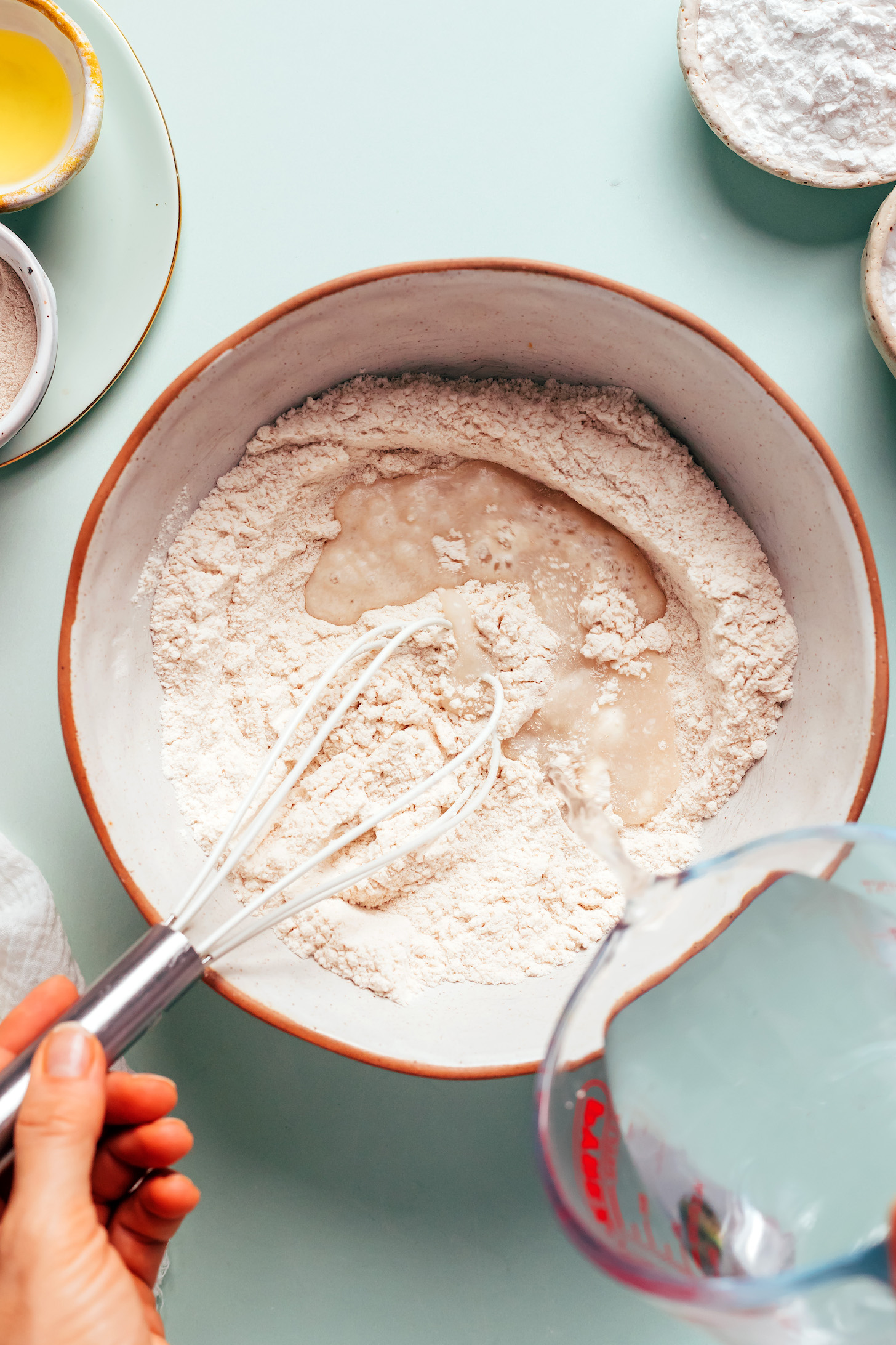Whisking water into a mixture of brown rice flour, yeast, and sugar