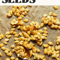 Homemade roasted pumpkin seeds on a baking sheet with text above that says how to roast pumpkin seeds step by step tutorial