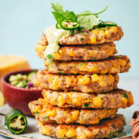 Stack of jalapeño corn fritters topped with cashew jalapeño sauce, cilantro, and jalapeño slices